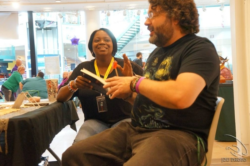 Michael and Rosalyn Lewis laughing as they sit behind a vendor table at a convention.